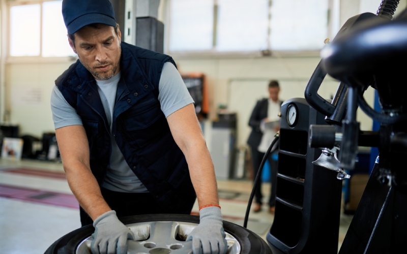 mid adult mechanic working with car tire auto repair shop 